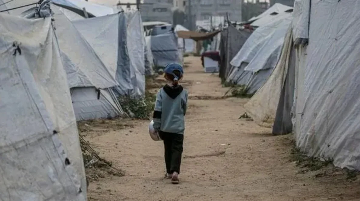 Enfant marchant entre des abris dans un camp de personnes déplacées